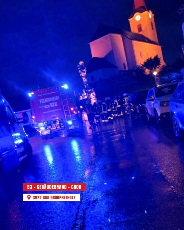 Einsatzfahrzeuge der Feuerwehr bei einem nächtlichen Einsatz im Regen mit Blaulicht.